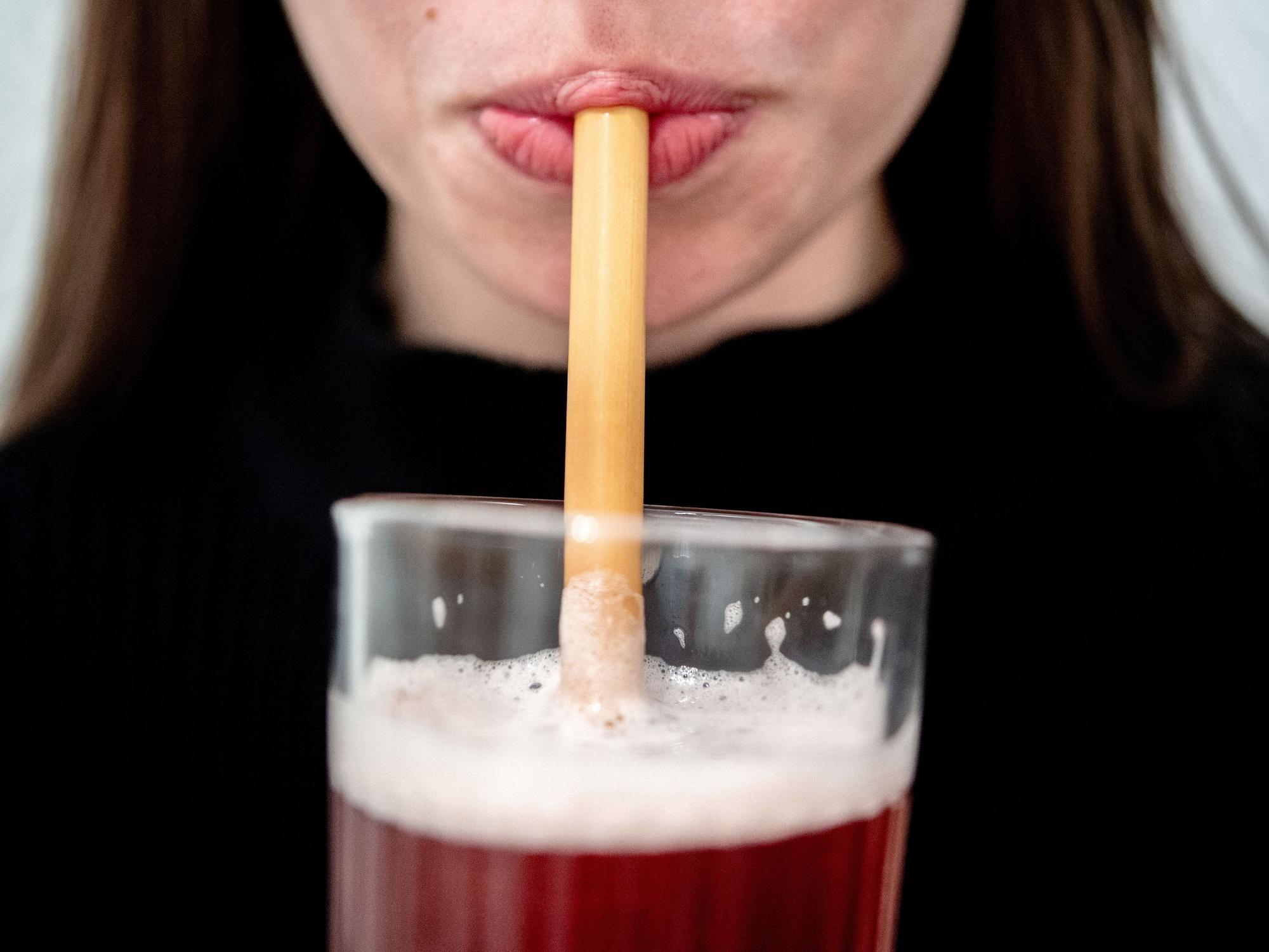 Junge Frau trinkt durch einen Strohhalm.