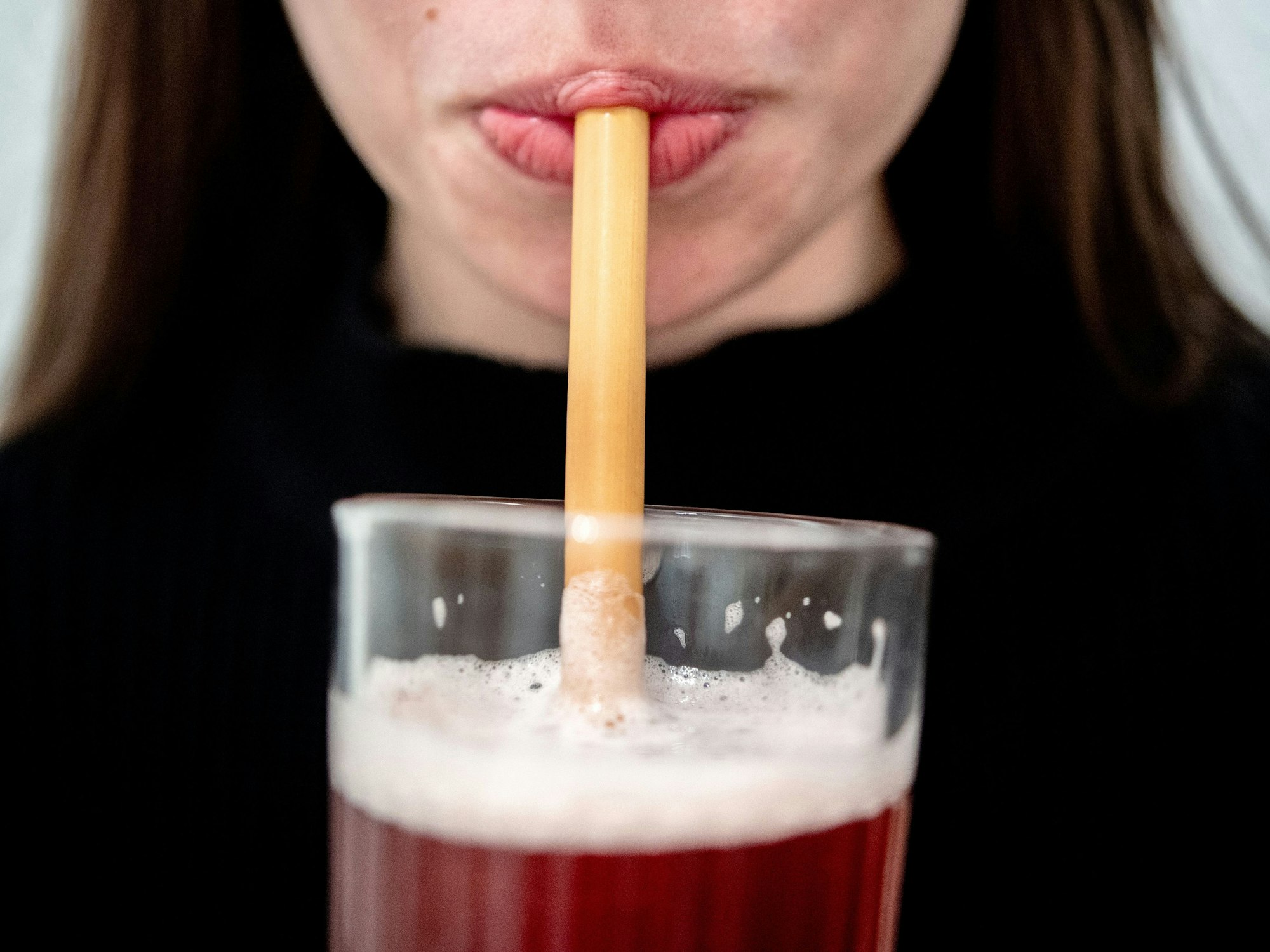 Junge Frau trinkt durch einen Strohhalm.