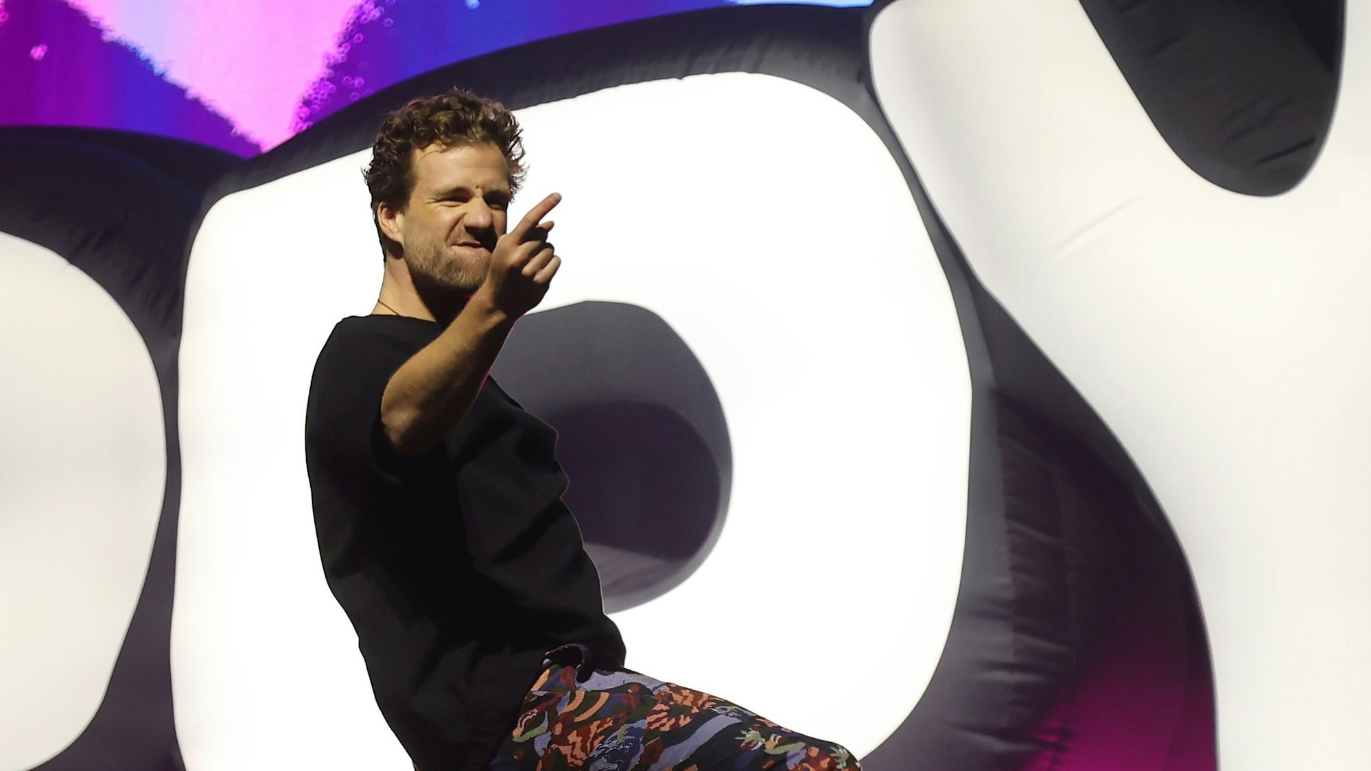 Luke Mockridge steht auf der Bühne der Lanxess Arena und zeigt mit einer Hand aufs Publikum.