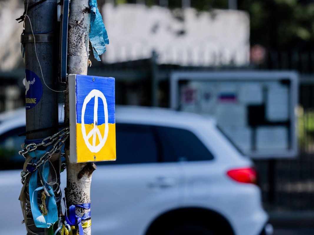 Ein Peace-Zeichen auf einer ukrainischen Flagge an einem Straßenschild in Bonn