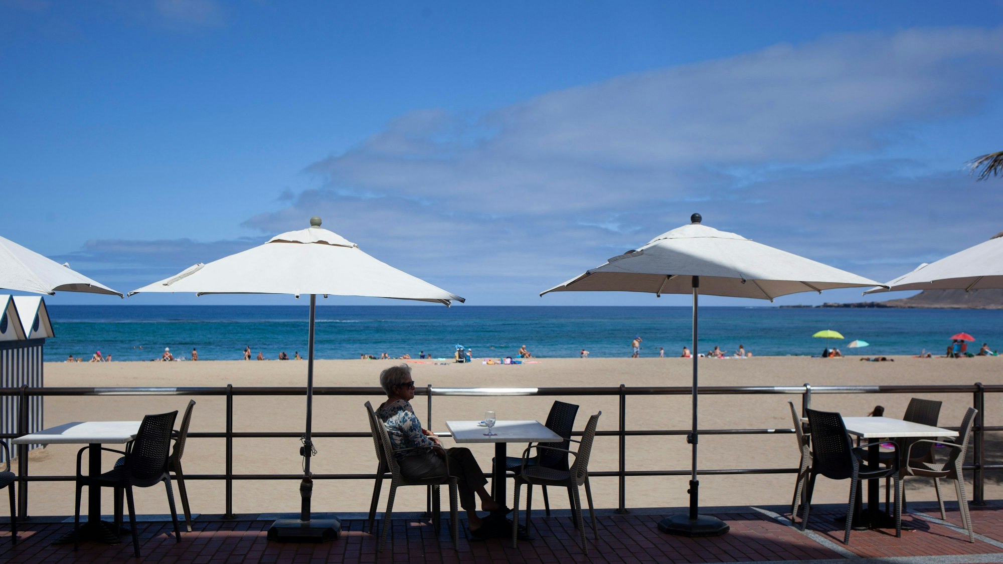 Eine Frau nimmt ein Getränk auf der Terrasse einer Bar am Strand in Las Palmas de Gran Canaria zu sich.