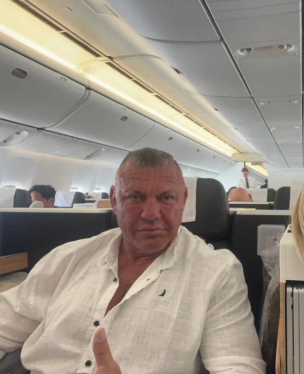 Caro und Andreas Robens sitzen im Flugzeug und schauen für ein Selfie in die Kamera.