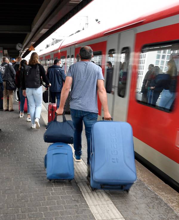 Bahnfahrende mit Koffern drängen sich am Eingang eines Regionalzuges.