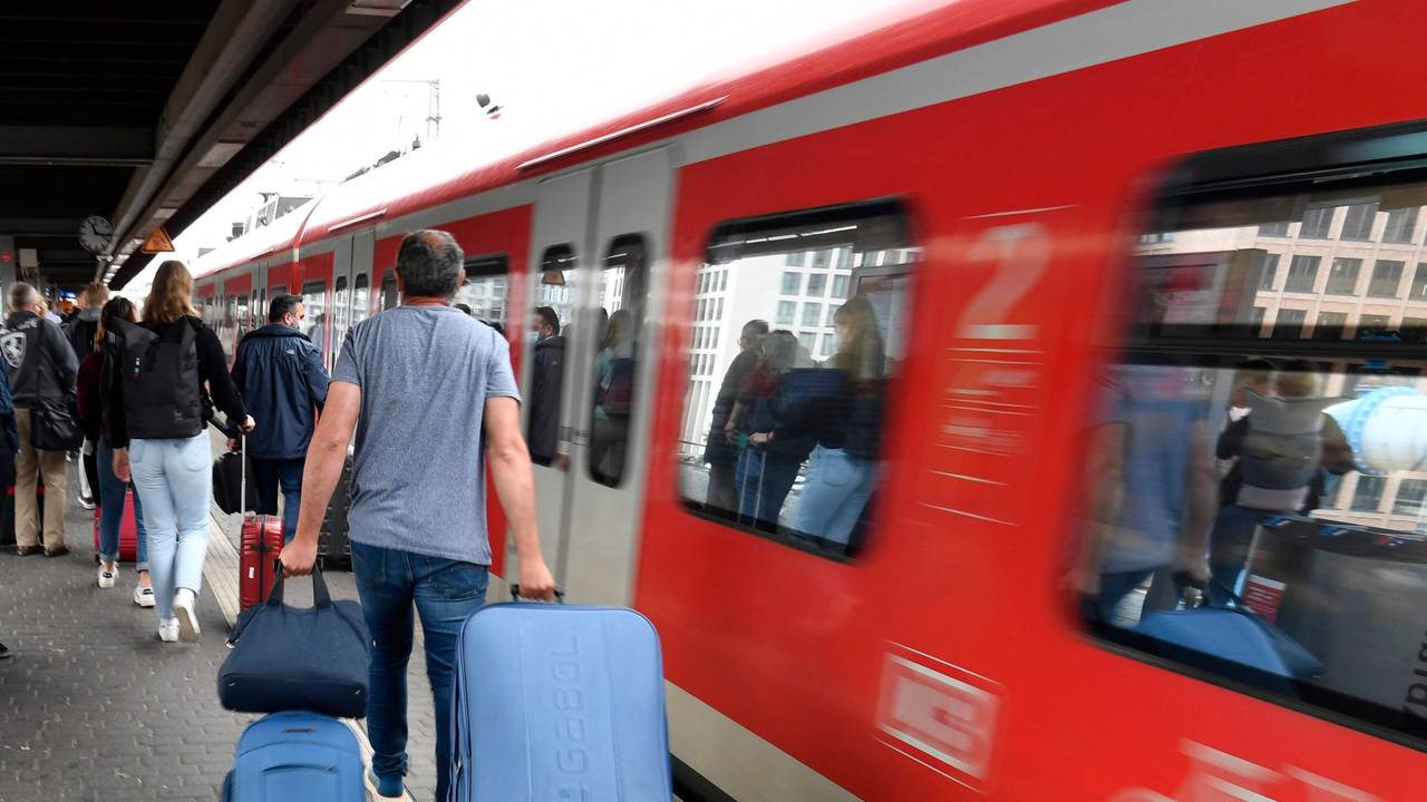 Bahnfahrende mit Koffern drängen sich am Eingang eines Regionalzuges.