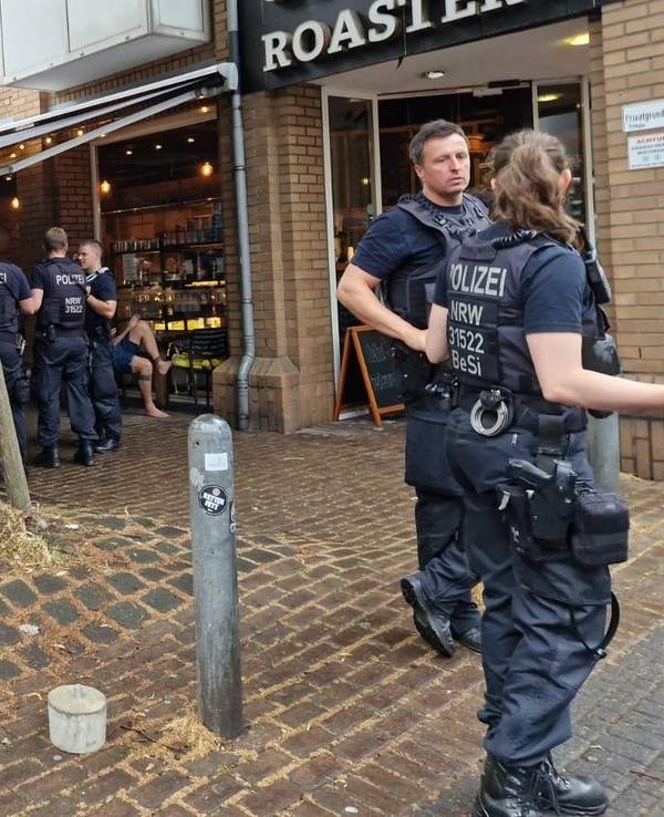 Polizisten und Polizistinnen stehen vor dem Café „Roastery“.