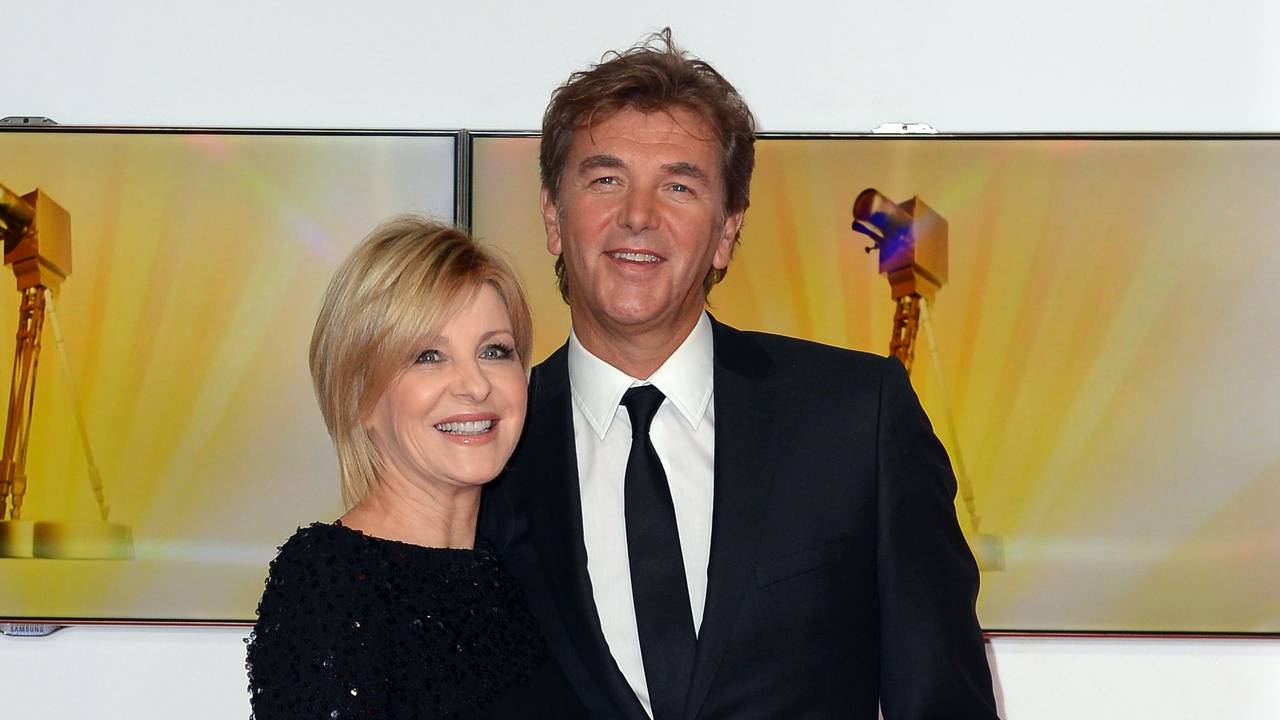 Carmen Nebel und Norbert Endlich posieren lächelnd in Gala-Kleidung auf dem roten Teppich der Goldenen Kamera