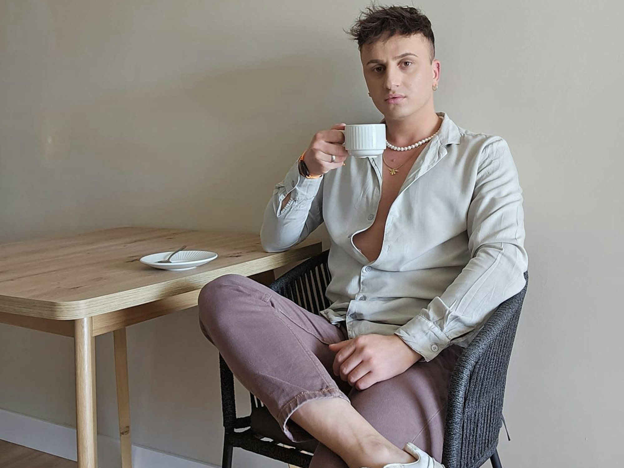 Mo Hartkopf sitzt auf einem Stuhl, in der Hand hält er eine Kaffeetasse.