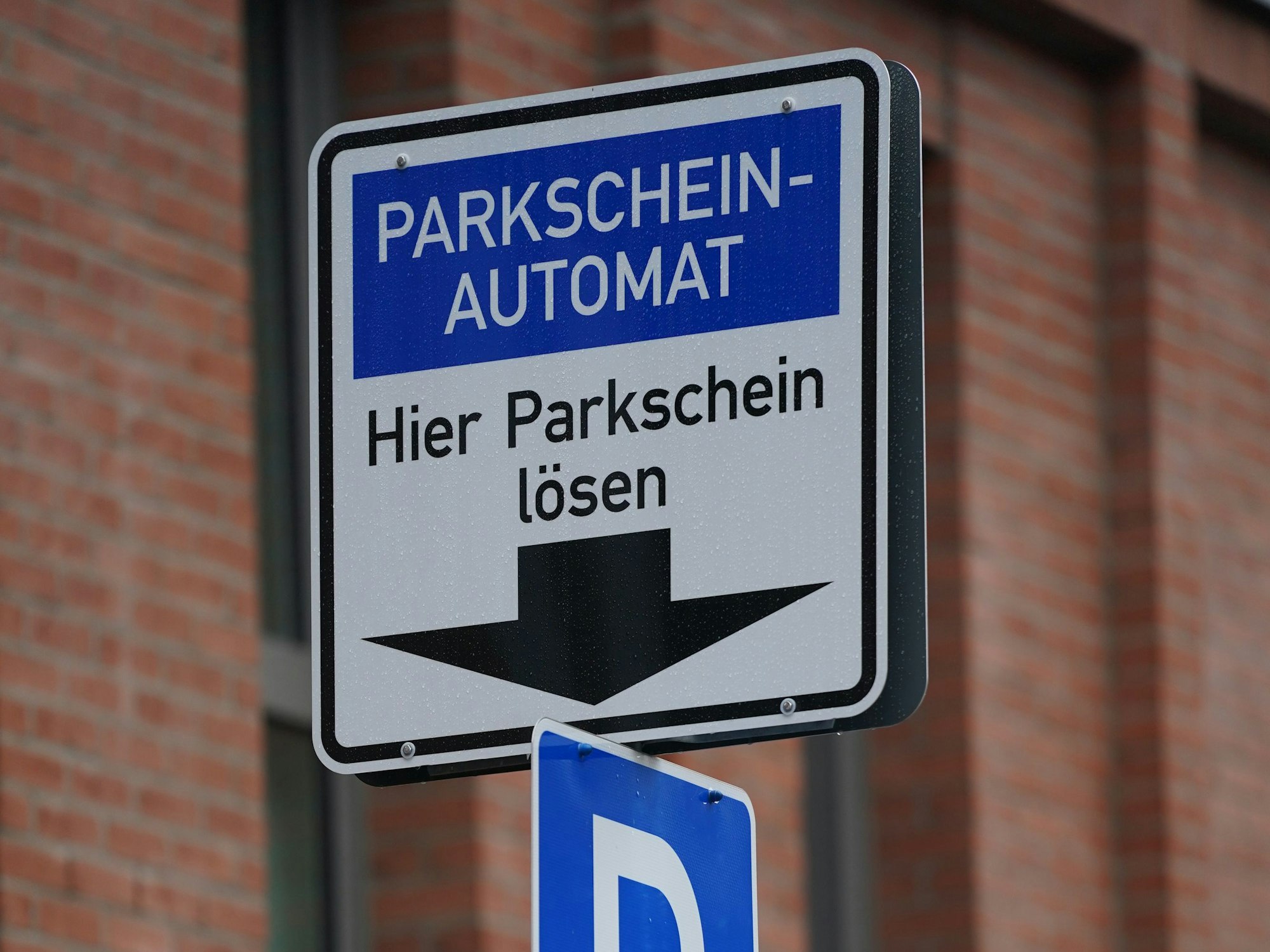 Ein Hinweisschild für einen Parkschein-Automaten ist an einer Straße zu sehen.