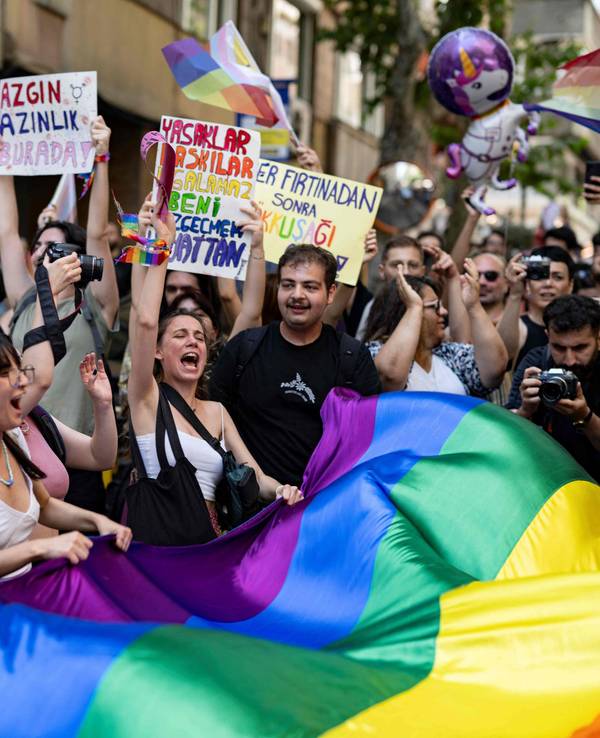 Menschen protestieren mit Schildern und einer großen Regenbogenflagge gegen die LGBTQ-feindliche Politik in der Türkei.