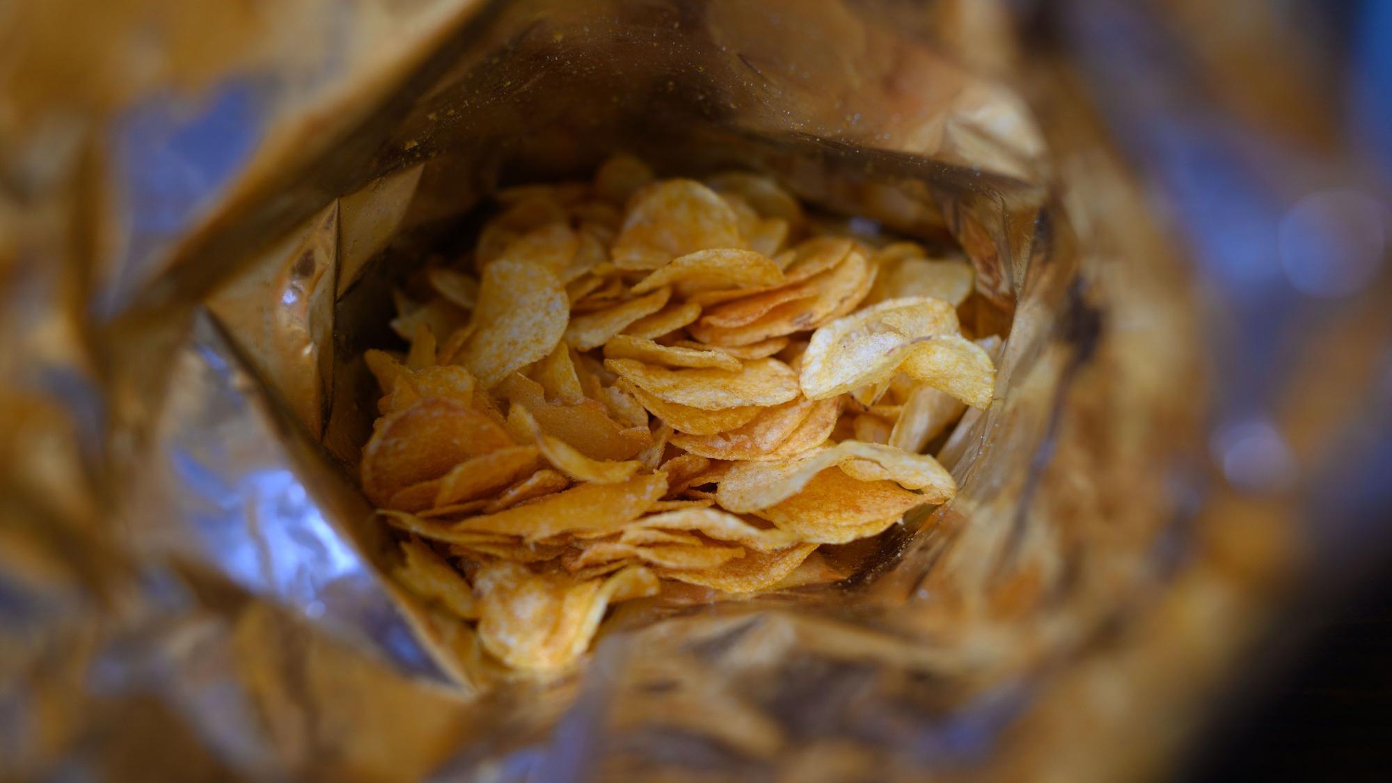 Eine offene Tüte Kartoffelchips liegt auf einem Tisch.