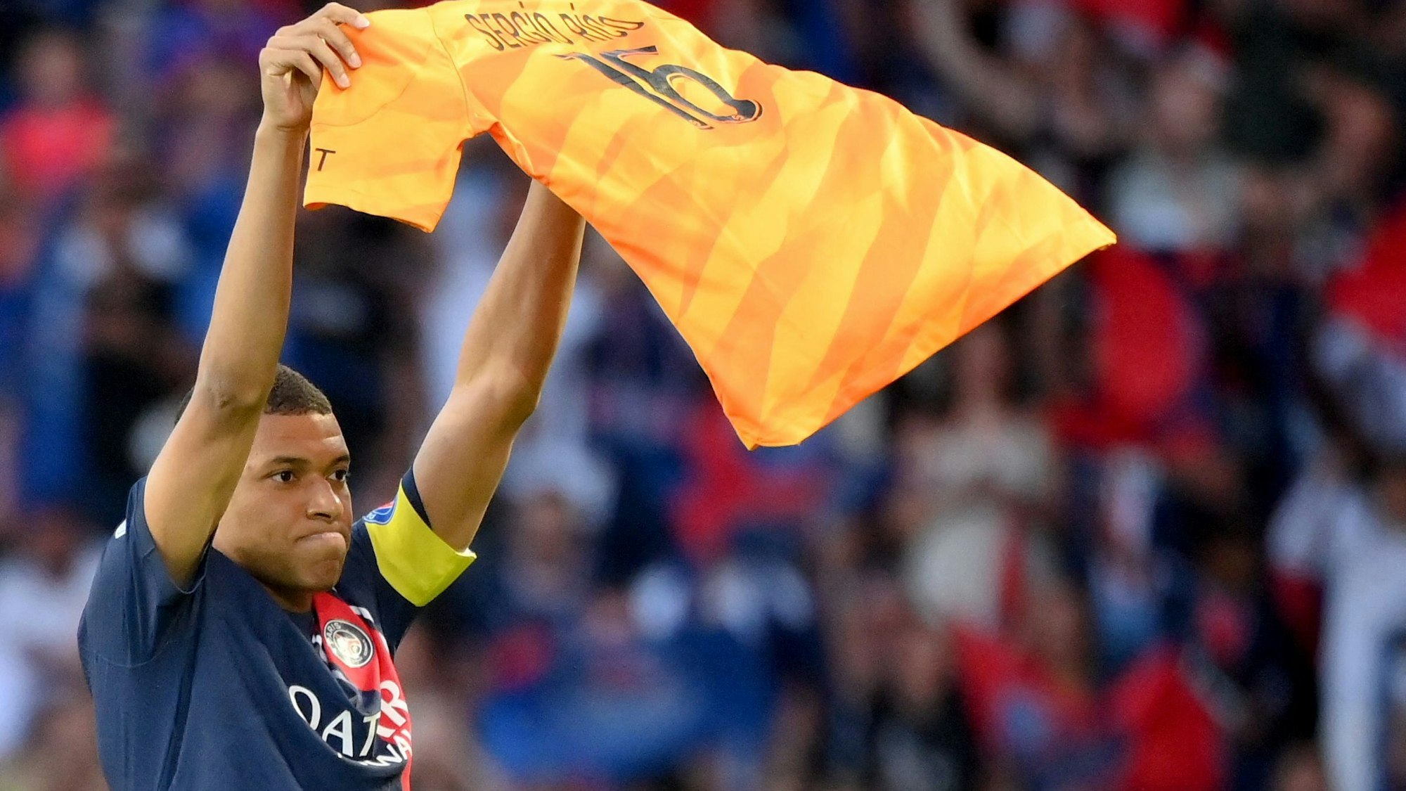Kylian Mbappe hält das Trikot von Sergio Rico hoch.
