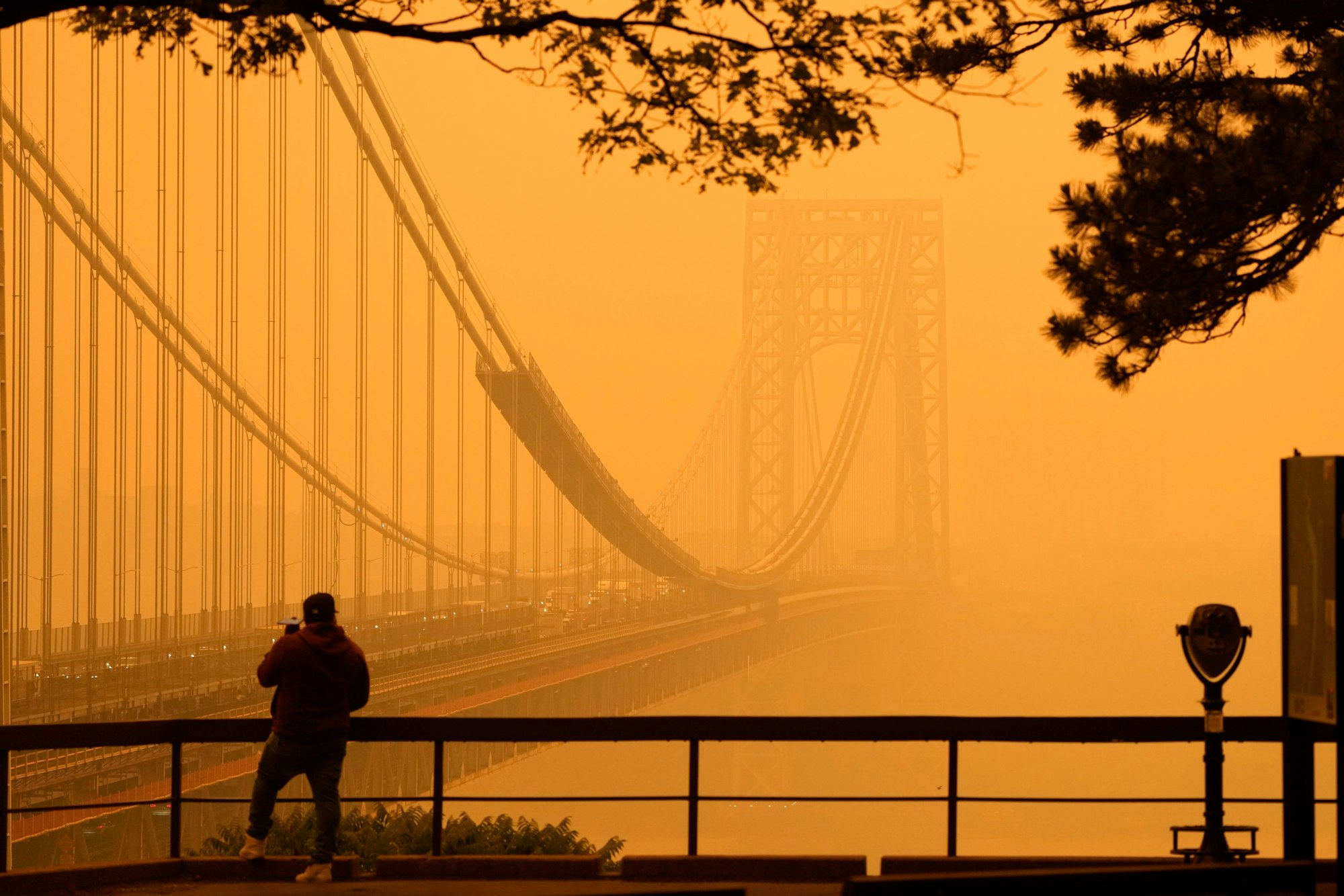 Ein Mann telefoniert, während er durch den Dunst vor der George Washington Bridge sieht.