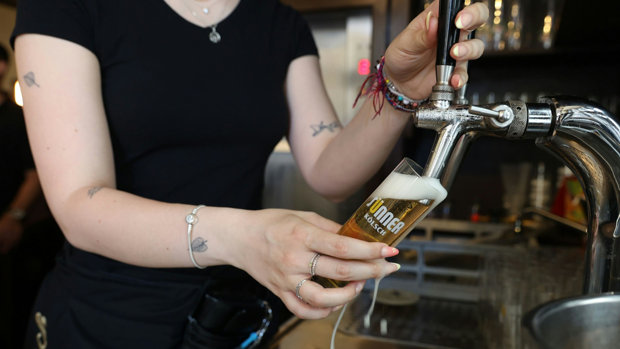 Eine Mitarbeiterin in einem Brauhaus zapft ein Kölsch.