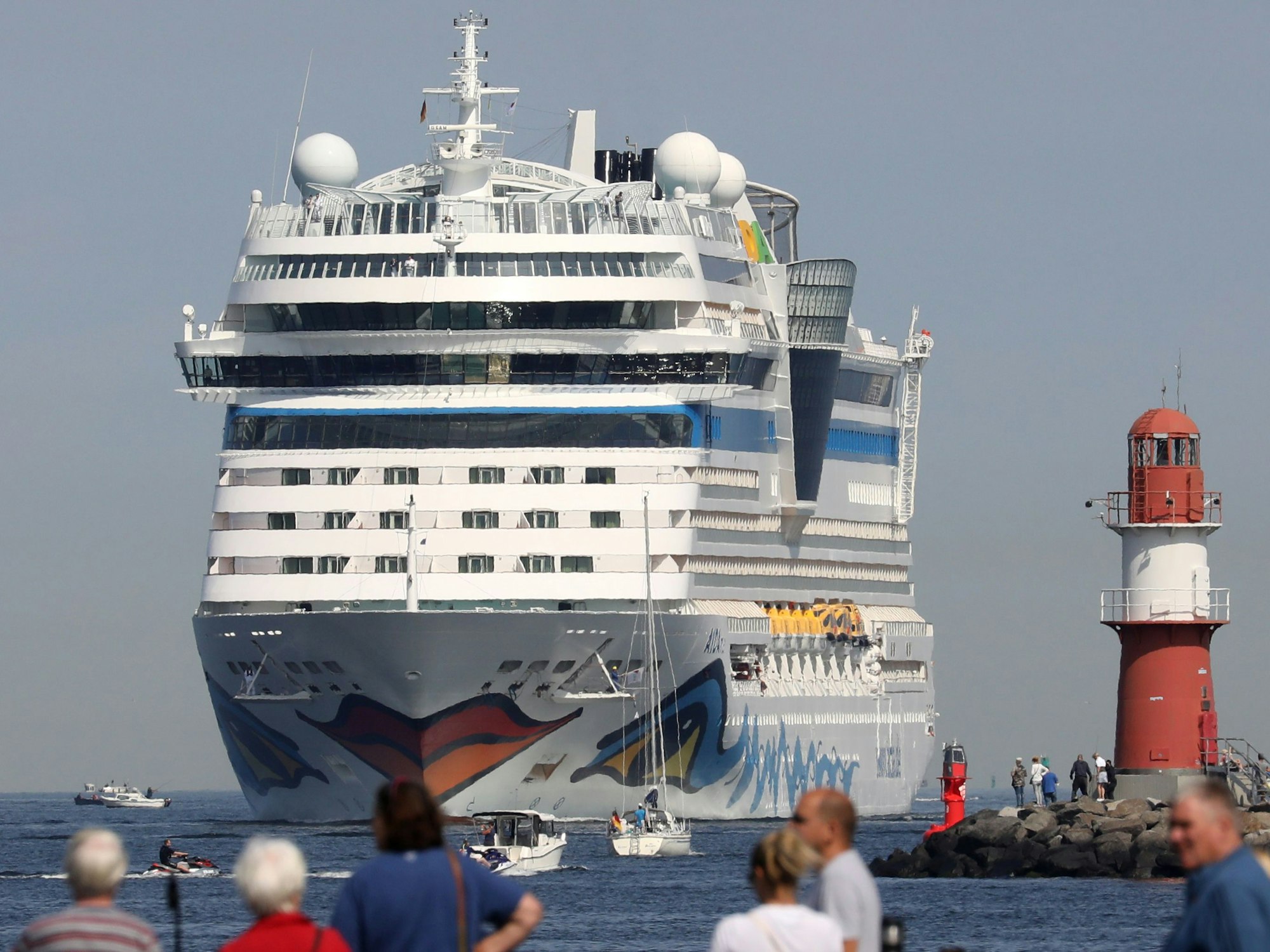 Die AIDAmar läuft in den Seekanal von Warnemünde ein, um im Seehafen festzumachen. Zahlreiche Schaulustige beobachten die Einfahrt.