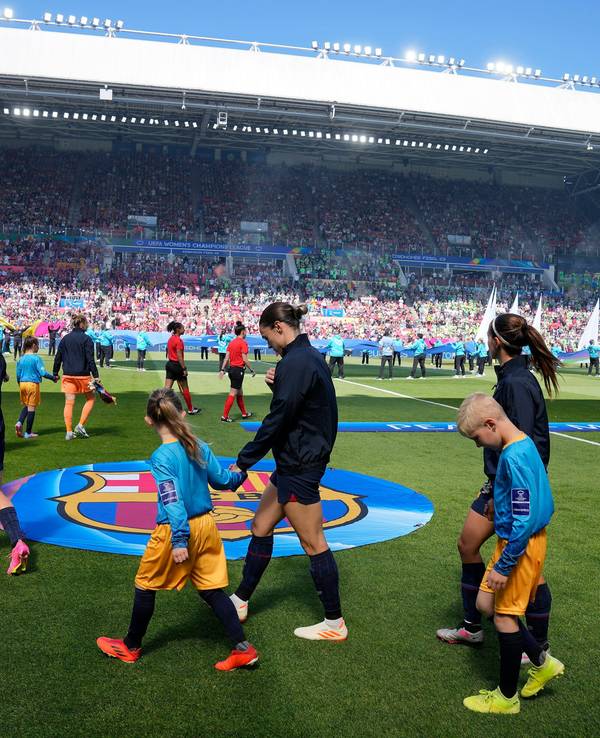 Die Spielerinnen des FC Barcelona laufen mit Kindern an der Hand auf den Rasen.