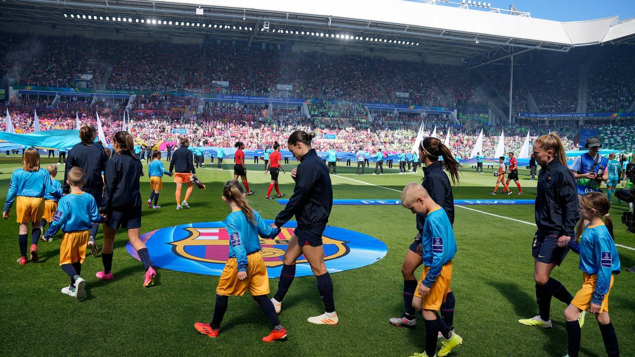 Die Spielerinnen des FC Barcelona laufen mit Kindern an der Hand auf den Rasen.