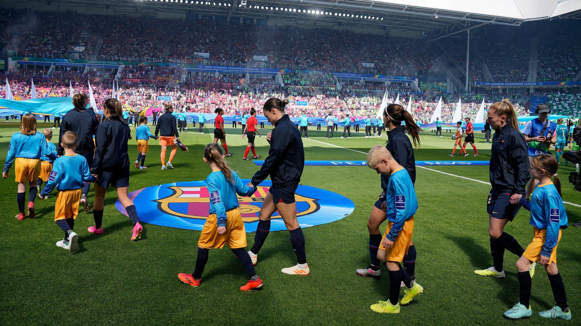 Die Spielerinnen des FC Barcelona laufen mit Kindern an der Hand auf den Rasen.