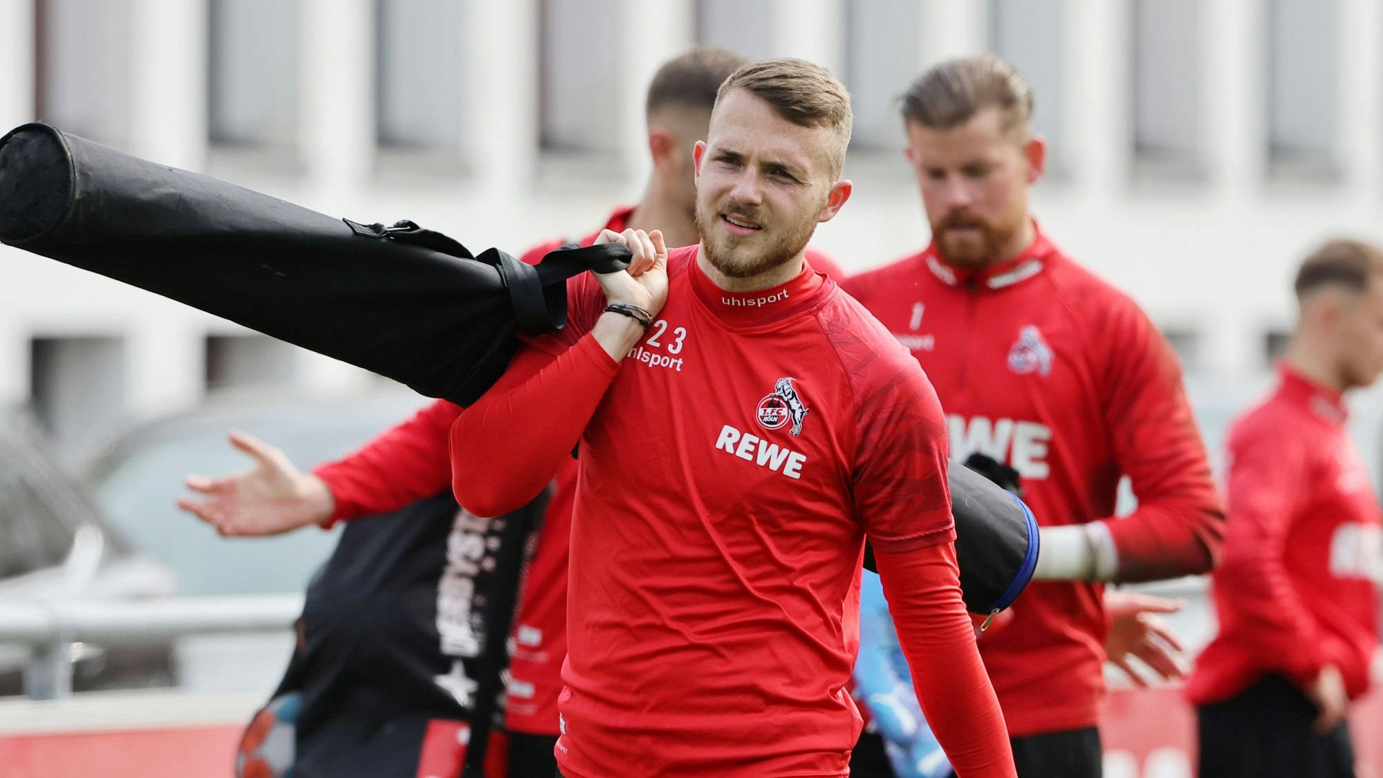 Jannes Horn trägt Trainingsmaterial über den Platz am Geißbockheim.