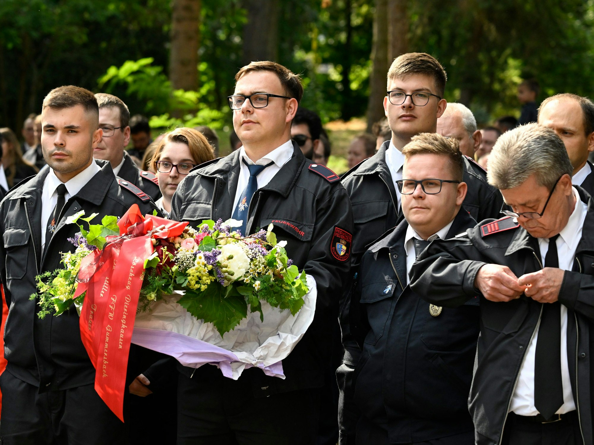 30.06.2023, Nordrhein-Westfalen, Sankt Augustin: Mit Blumen verabschieden Feuerwehrleute aus ganz Deutschland bei der Trauerfeier ihre verstorbenen Kameraden.