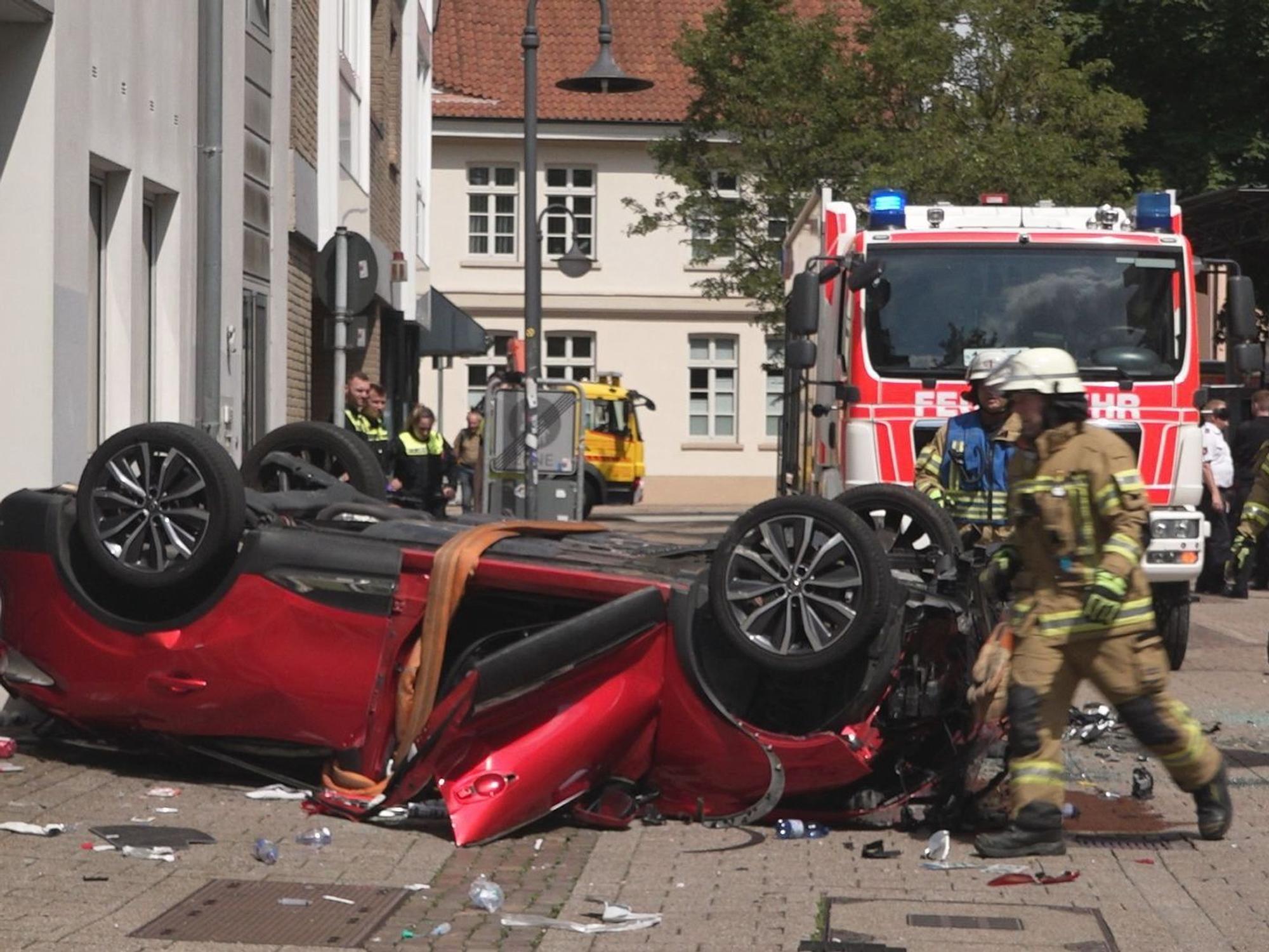 Vor einem Parkhaus in Oldenburg liegt am 30. Juni 2023 ein Auto auf dem Dach. Der Wagen war aus dem vierten Stock des Parkhauses auf die Straße gefallen.