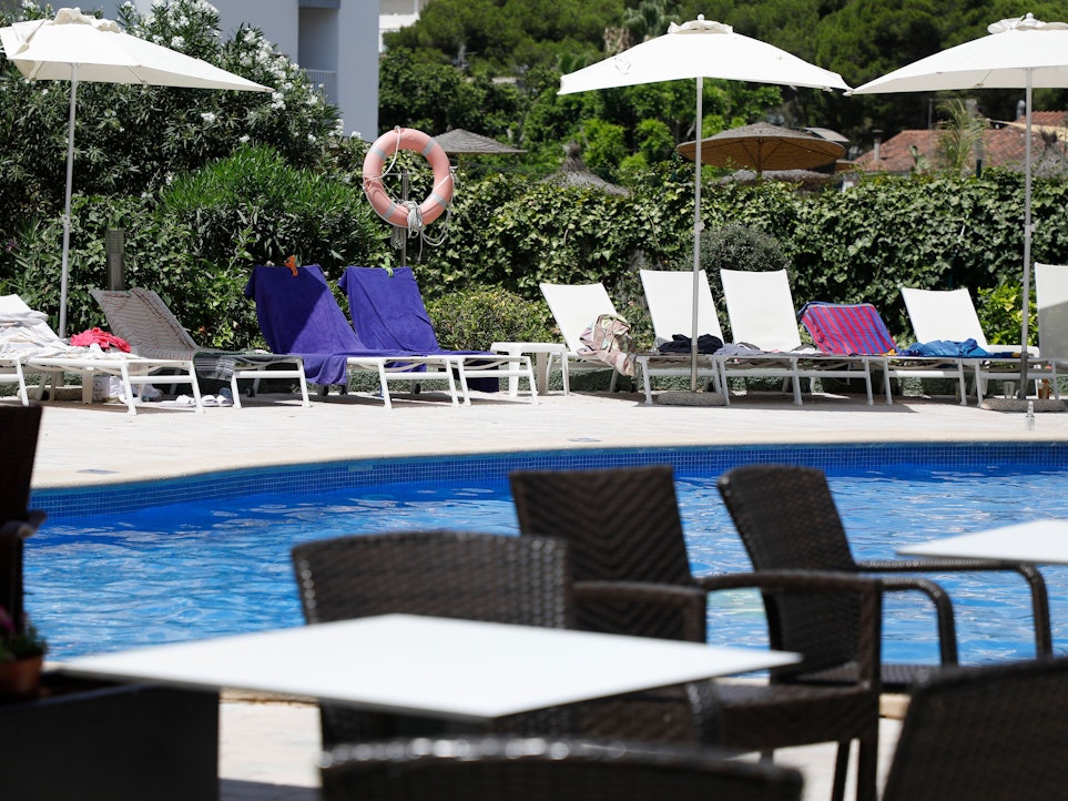 Handtücher liegen auf Sonnenliegen an einem Pool.