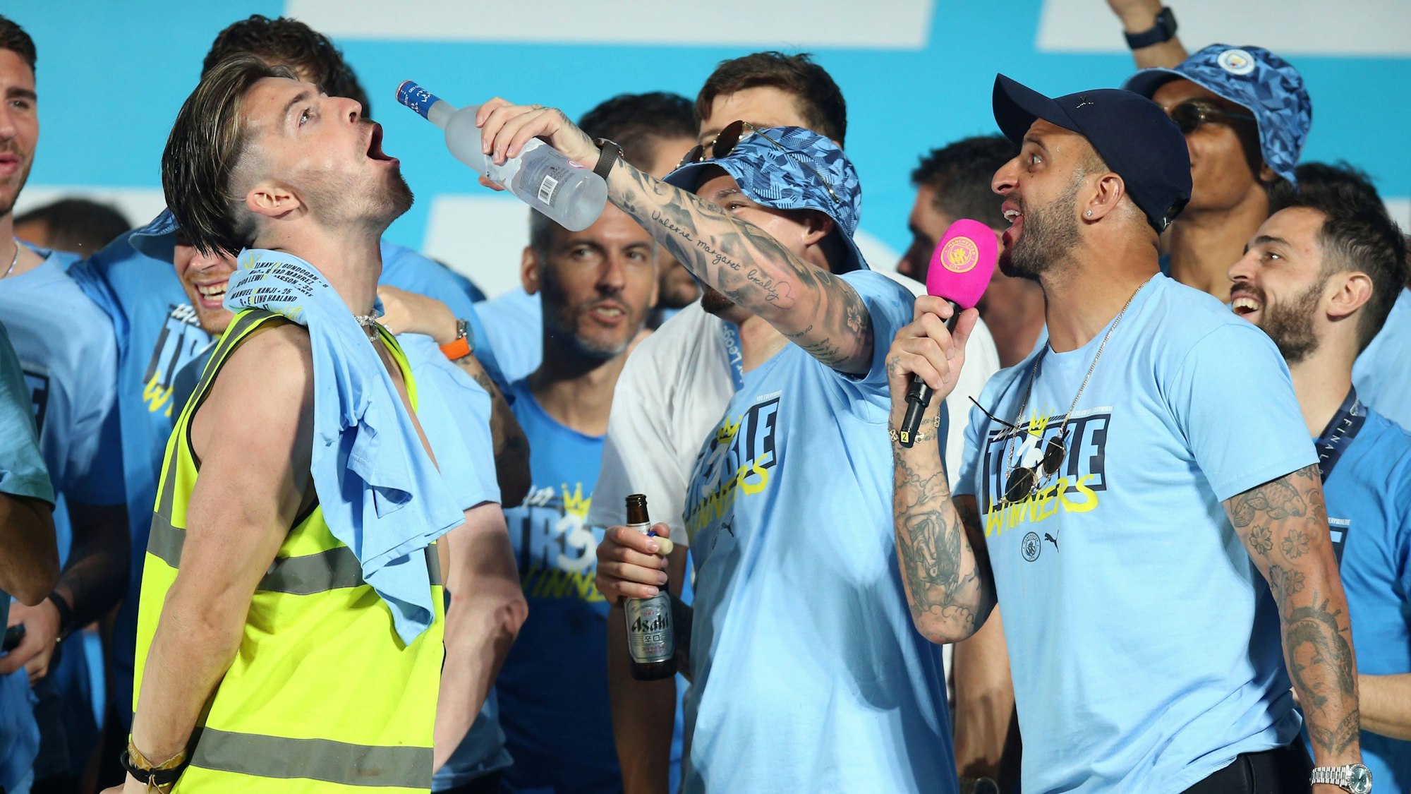 Jack Grealish lässt sich Alkohol schmecken, Kalvin Phillips gibt ihm einen Schluck aus der Flasche, Kyle Walker kommentiert das Ganze.