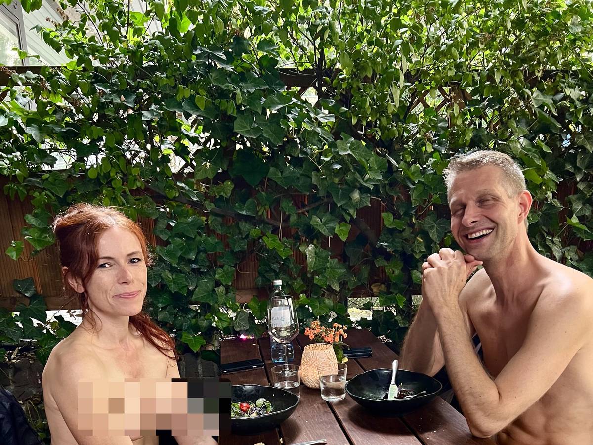 Ein nackter Mann sitzt zusammen mit einer nackten Frau in Köln an einem Restaurant-Tisch.