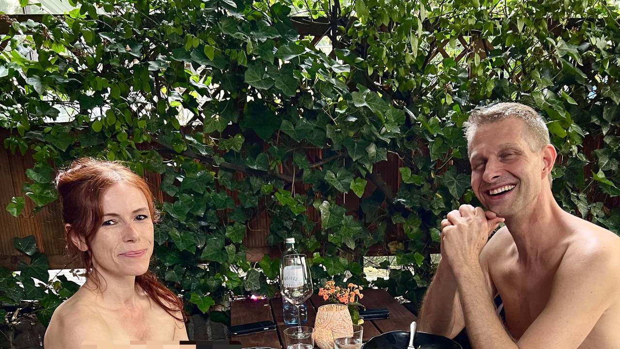 Ein nackter Mann sitzt zusammen mit einer nackten Frau in Köln an einem Restaurant-Tisch.