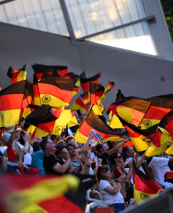 Deutschland-Fans schwingen Fahnen auf der Tribüne.