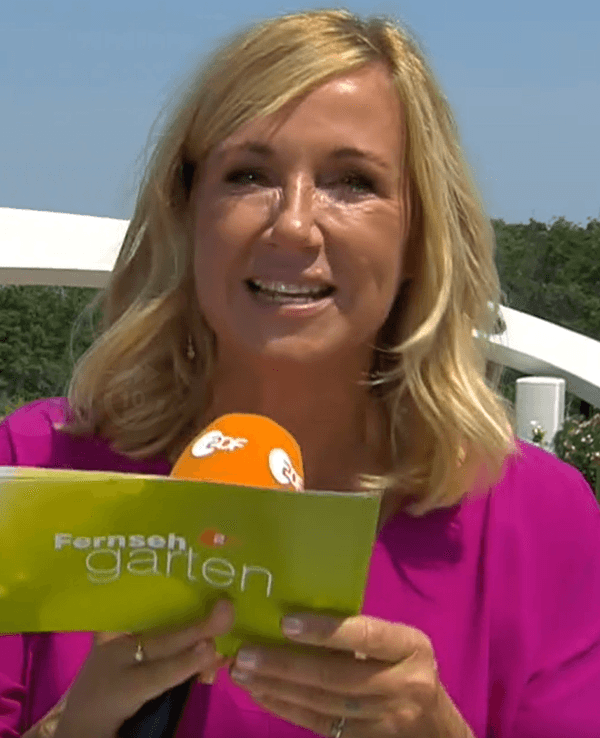 Andrea Kiewel hält eine Moderationskarte und ein Mikrofon in der Hand.
