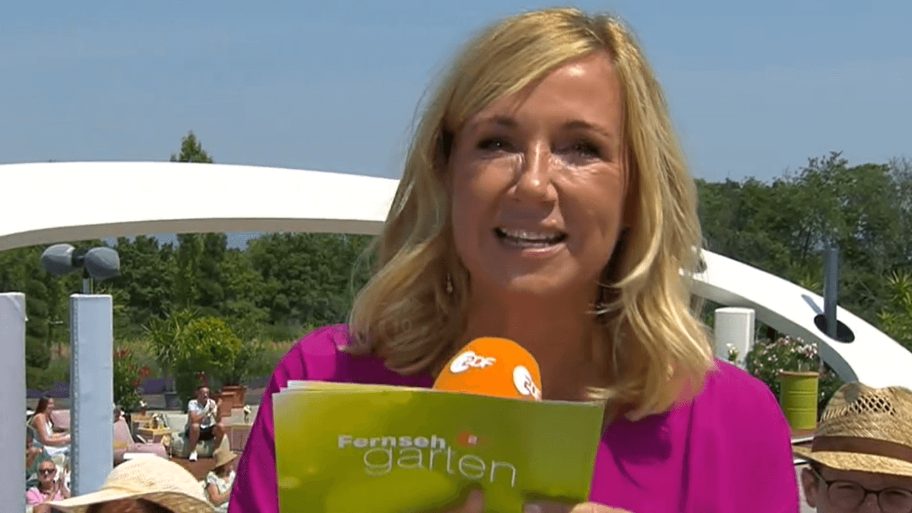 Andrea Kiewel hält eine Moderationskarte und ein Mikrofon in der Hand.