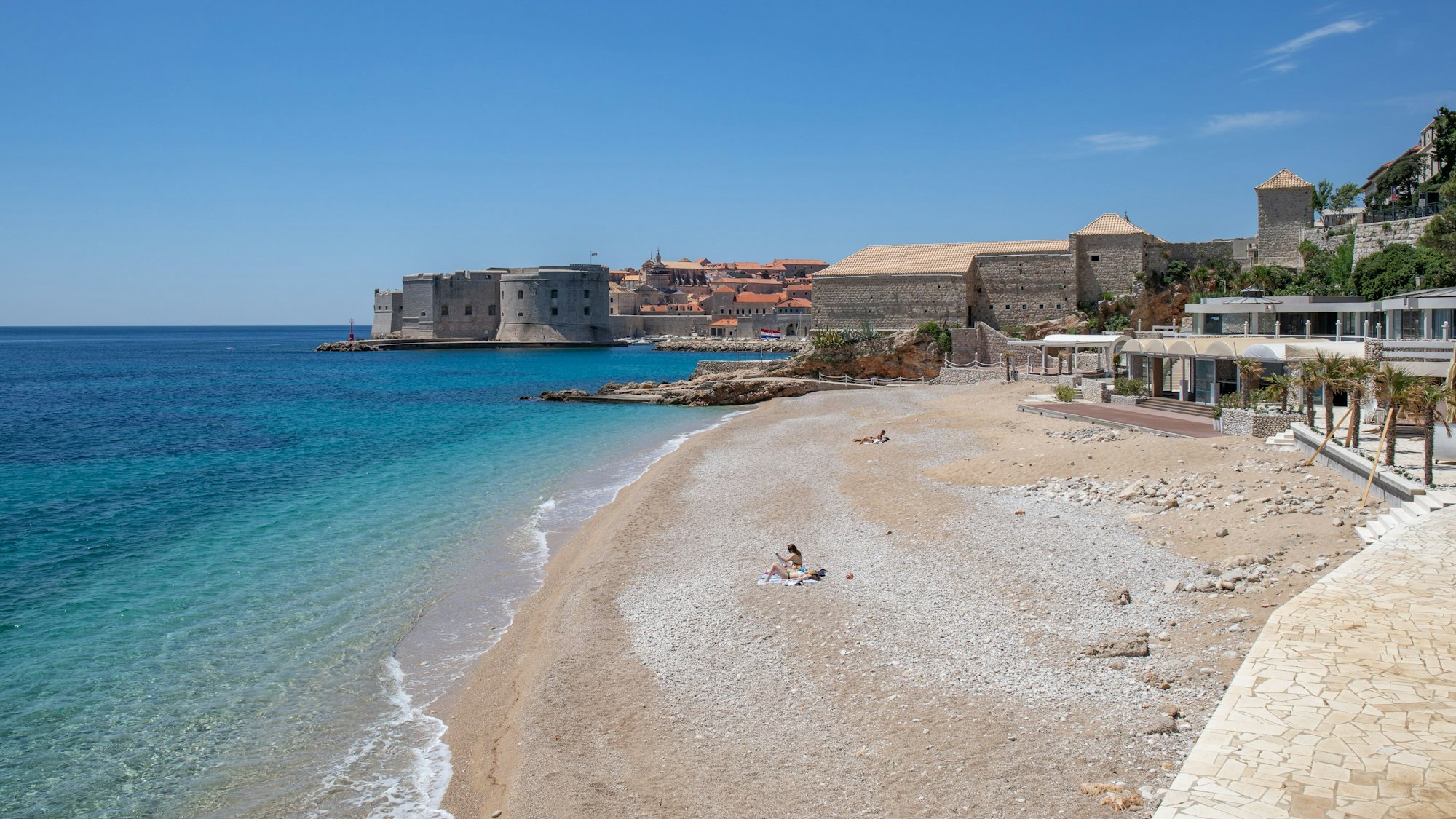 Vier Personen sonnen sich an einem Strand in Dubrovnik.