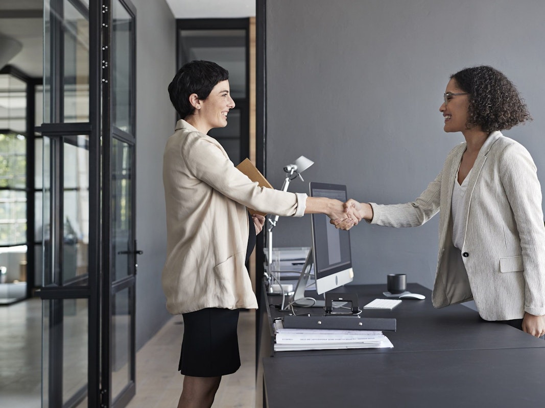 Zwei Frauen schütteln sich die Hände.