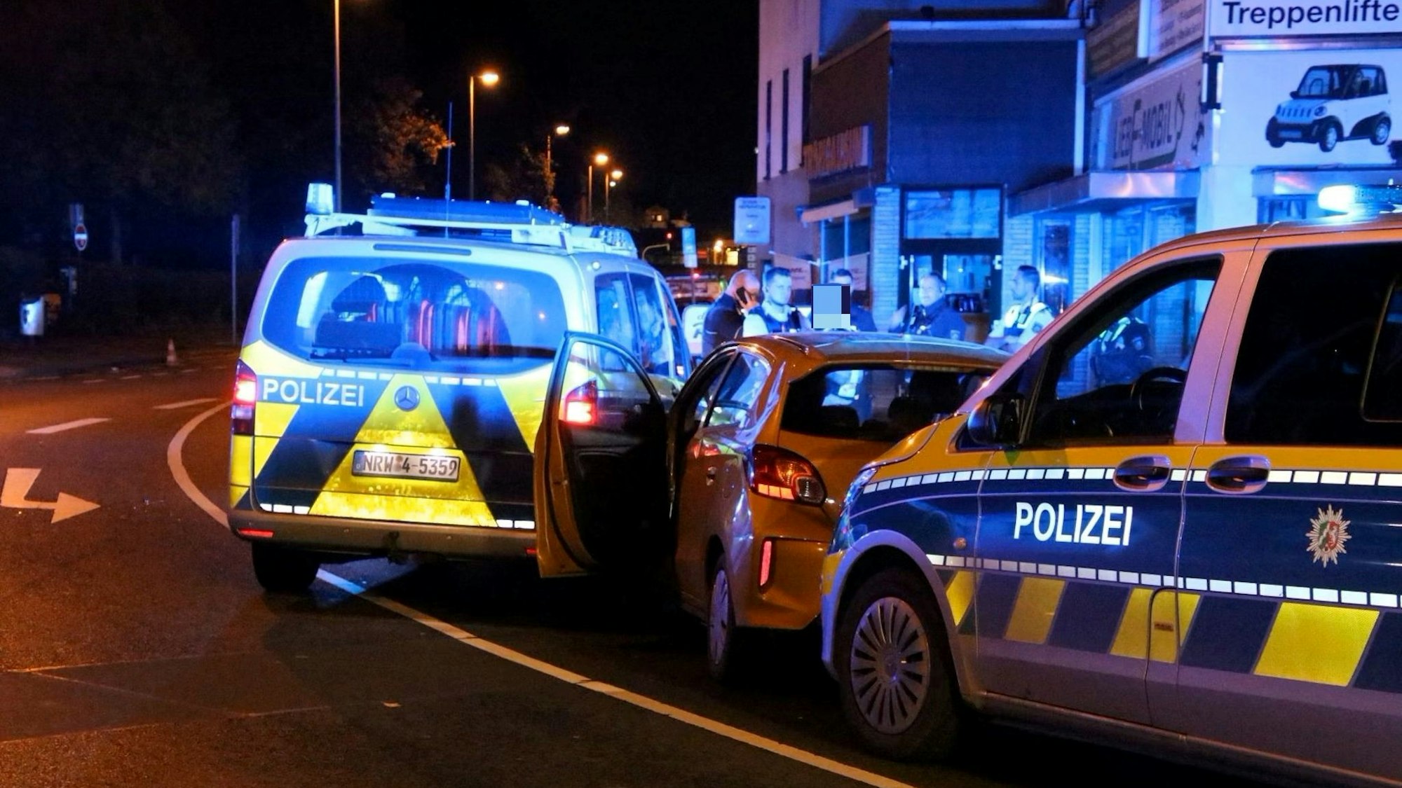 Ein Auto steht auf der Straße, vor und hinter ihm Polizeifahrzeuge.