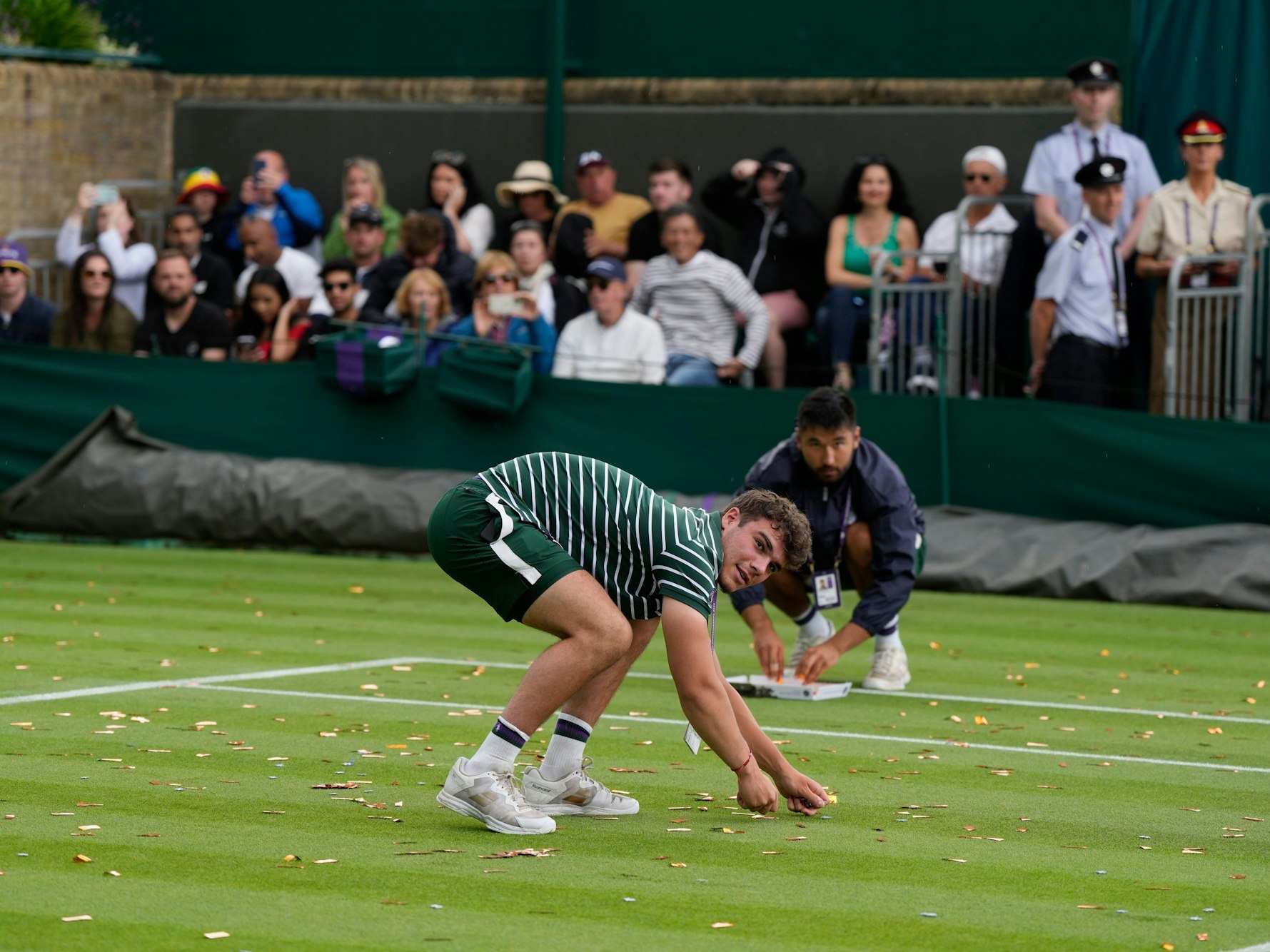 Ein Balljunge sammelt Konfetti-Schnipsel auf, die eine Klimaaktivistin und ein Klimaaktivist auf dem Platz verteilt hatten.