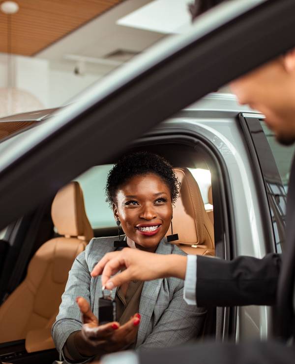 Close up of a mature woman talking to the car salesman about a car purchase while checking out the car