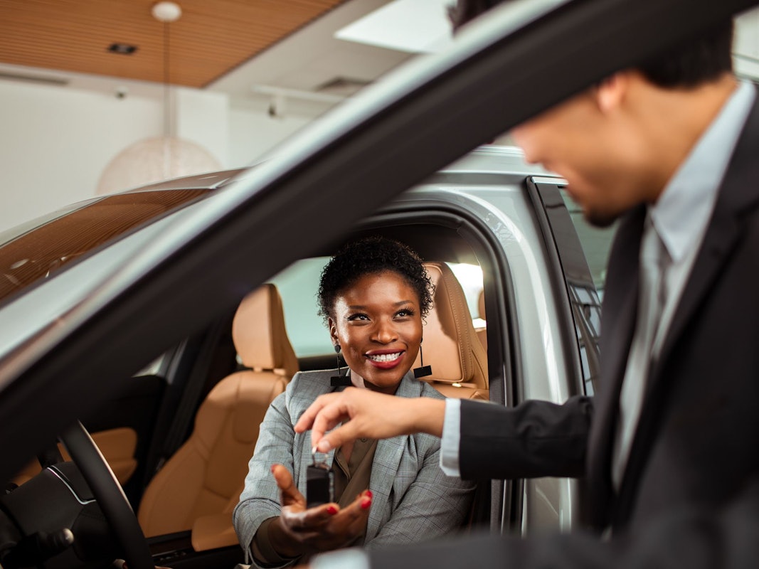 Close up of a mature woman talking to the car salesman about a car purchase while checking out the car