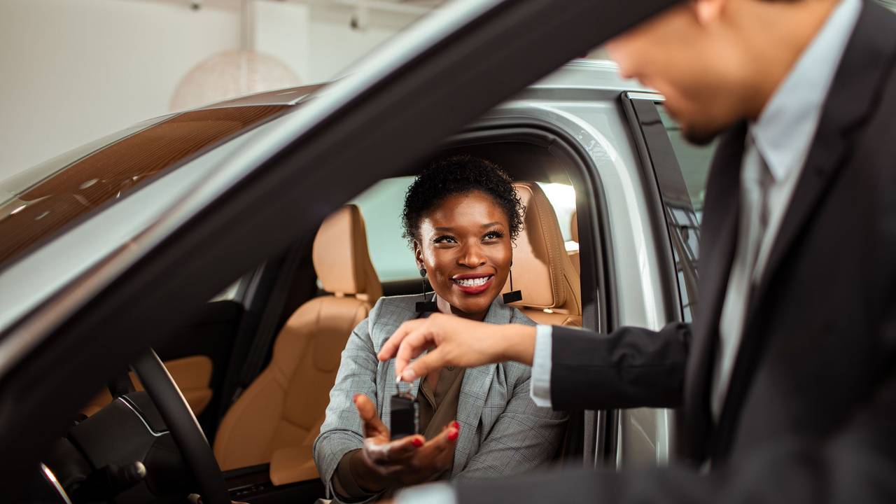 Close up of a mature woman talking to the car salesman about a car purchase while checking out the car