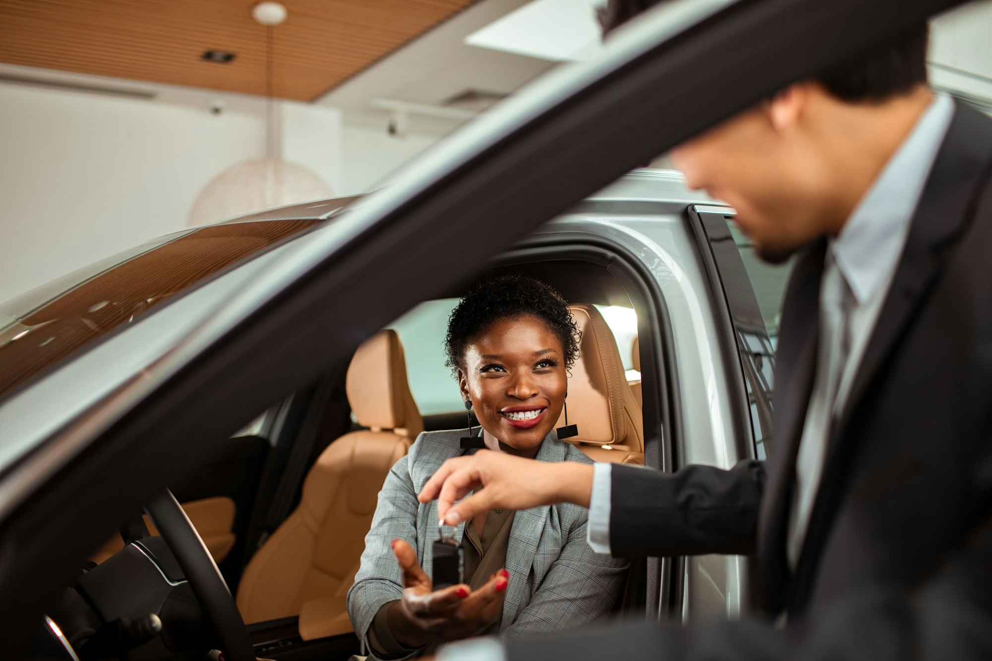 Close up of a mature woman talking to the car salesman about a car purchase while checking out the car