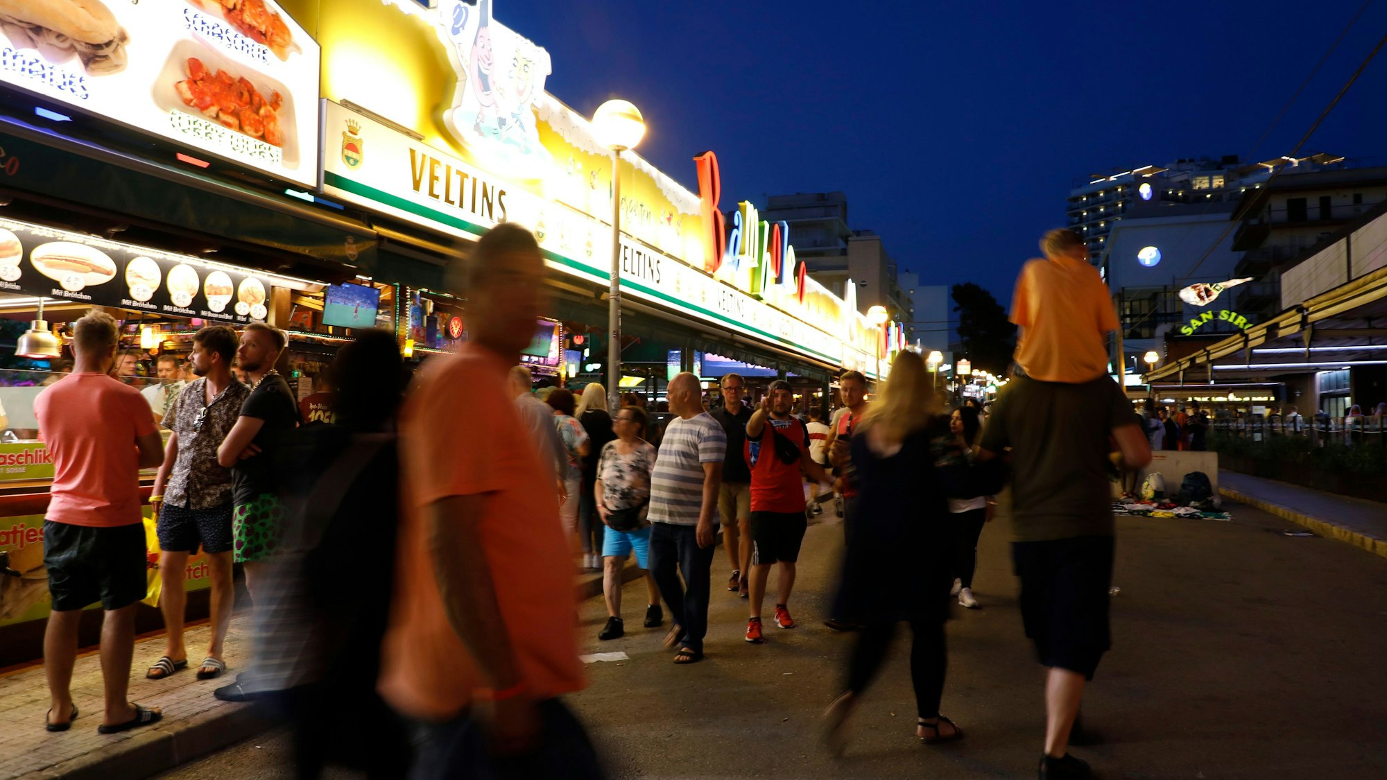 Menschen gehen im Mai 2022 an der Bar Bamboleo in der Bierstraße am Ballermann vorbei.
