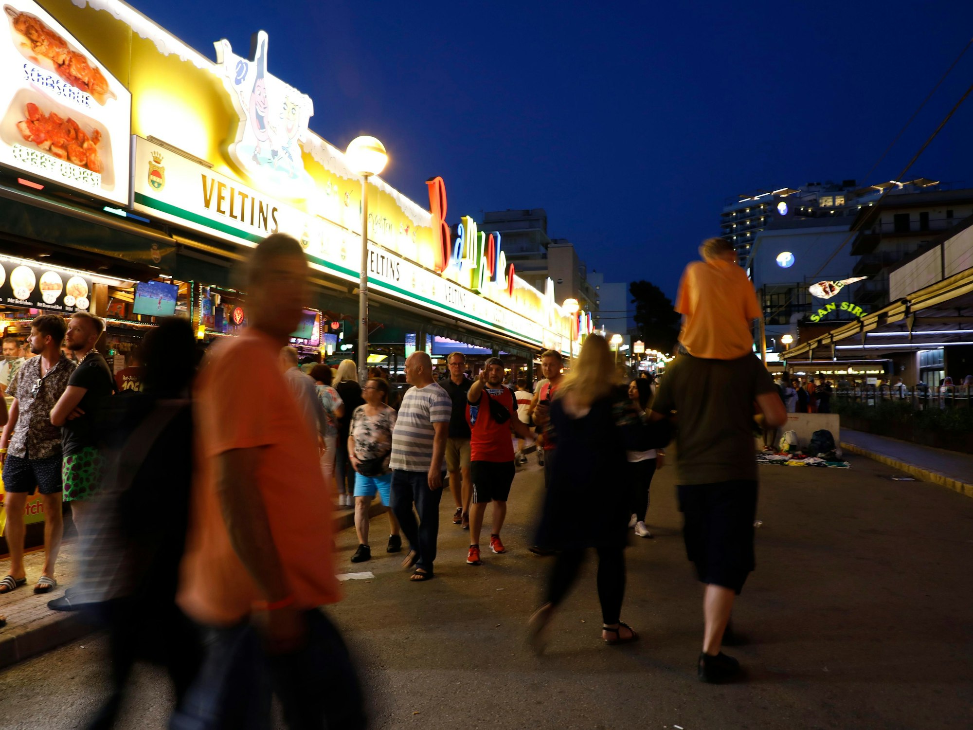 Menschen gehen im Mai 2022 an der Bar Bamboleo in der Bierstraße am Ballermann auf Mallorca vorbei.