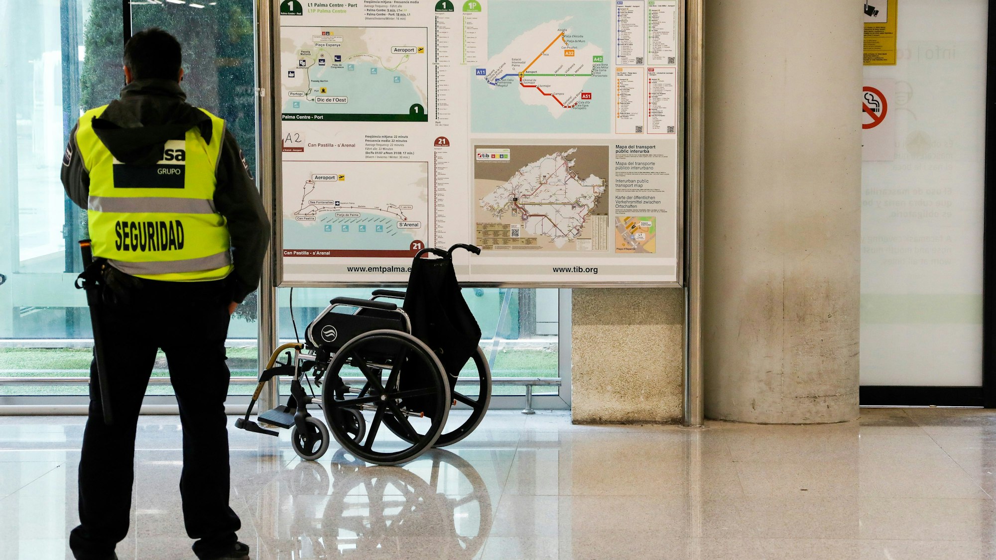 Ein Sicherheitsmann steht am Flughafen von Palma de Mallorca vor einem Rollstuhl
