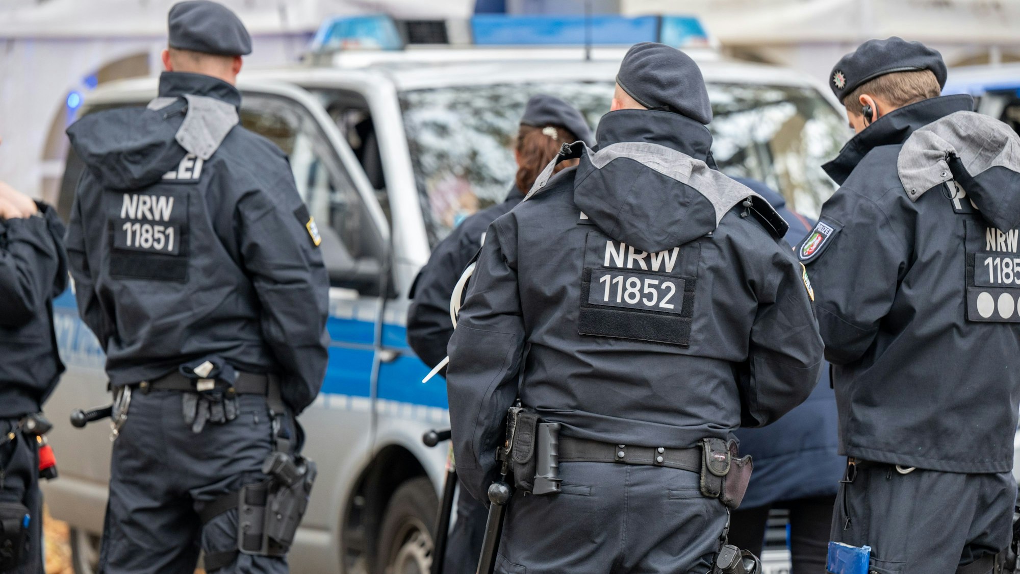Polizisten stehen an Einsatzfahrzeuge.