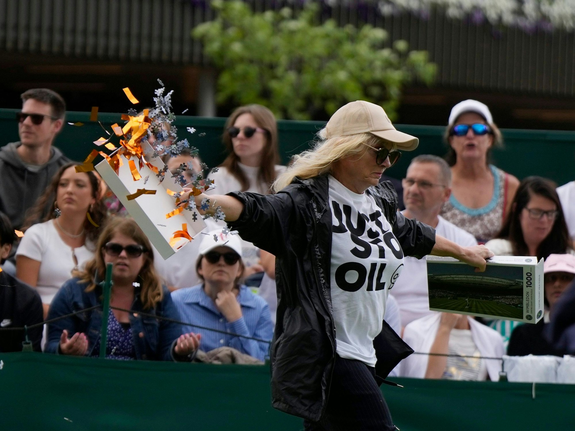 Eine Klimaaktivistin verteilt auf Court 18 in Wimbledon Konfetti-Schnipsel und Puzzle-Teile.