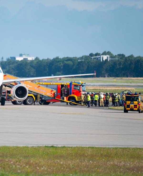Ein Flugzeug steht auf dem Rollfeld, daneben ein Feuerwehrauto und Einsatzkräfte.