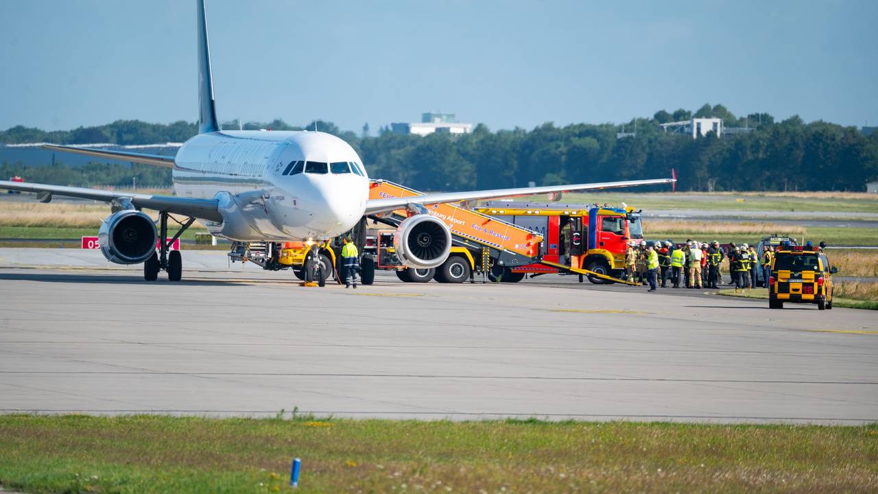 Ein Flugzeug steht auf dem Rollfeld, daneben ein Feuerwehrauto und Einsatzkräfte.