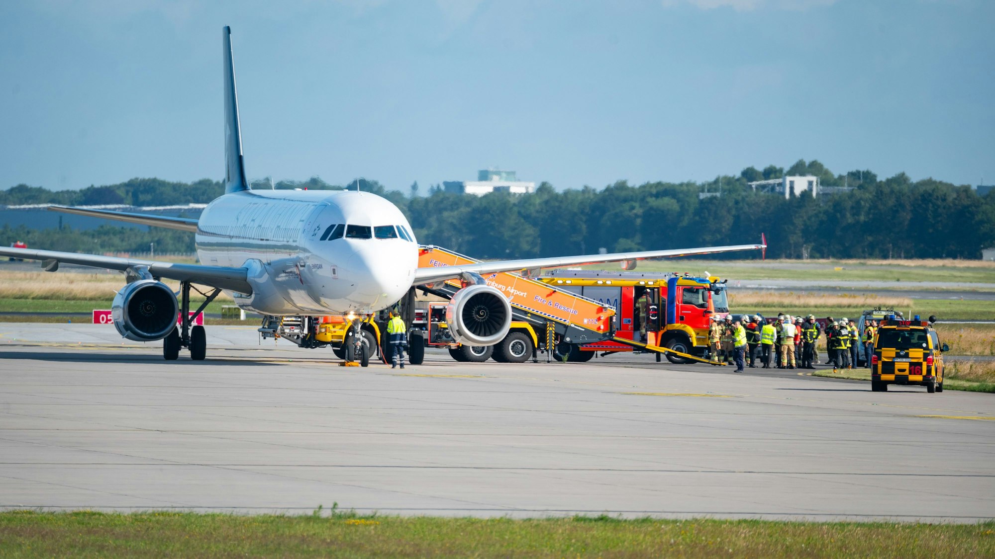 Ein Flugzeug steht auf dem Rollfeld, daneben ein Feuerwehrauto und Einsatzkräfte.