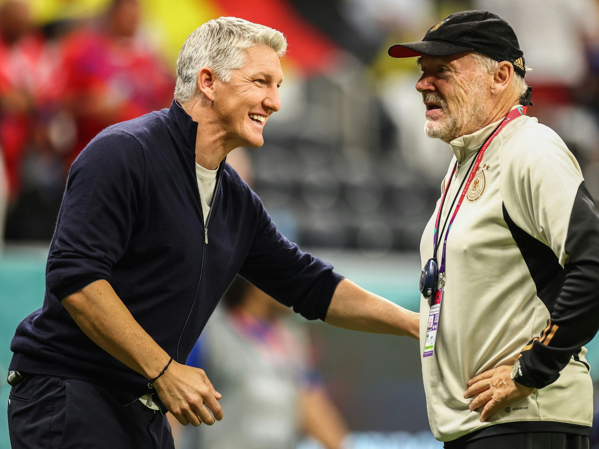 Bastian Schweinsteiger unterhält sich mit Hermann Gerland. Beide lachen.