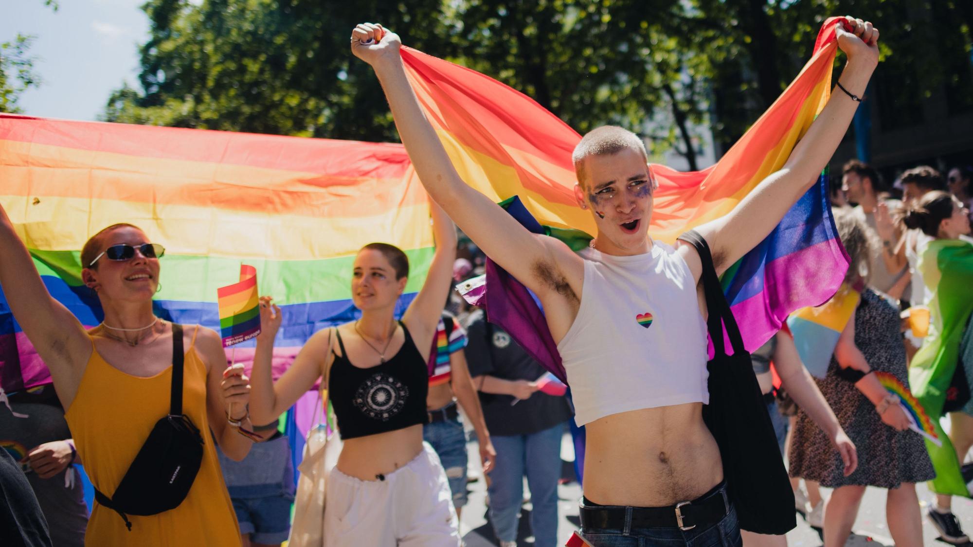 Teilnehmer einer Parade zum Christopher Street Day (CSD) ziehen mit Regenbogenfahnen durch die Stadt