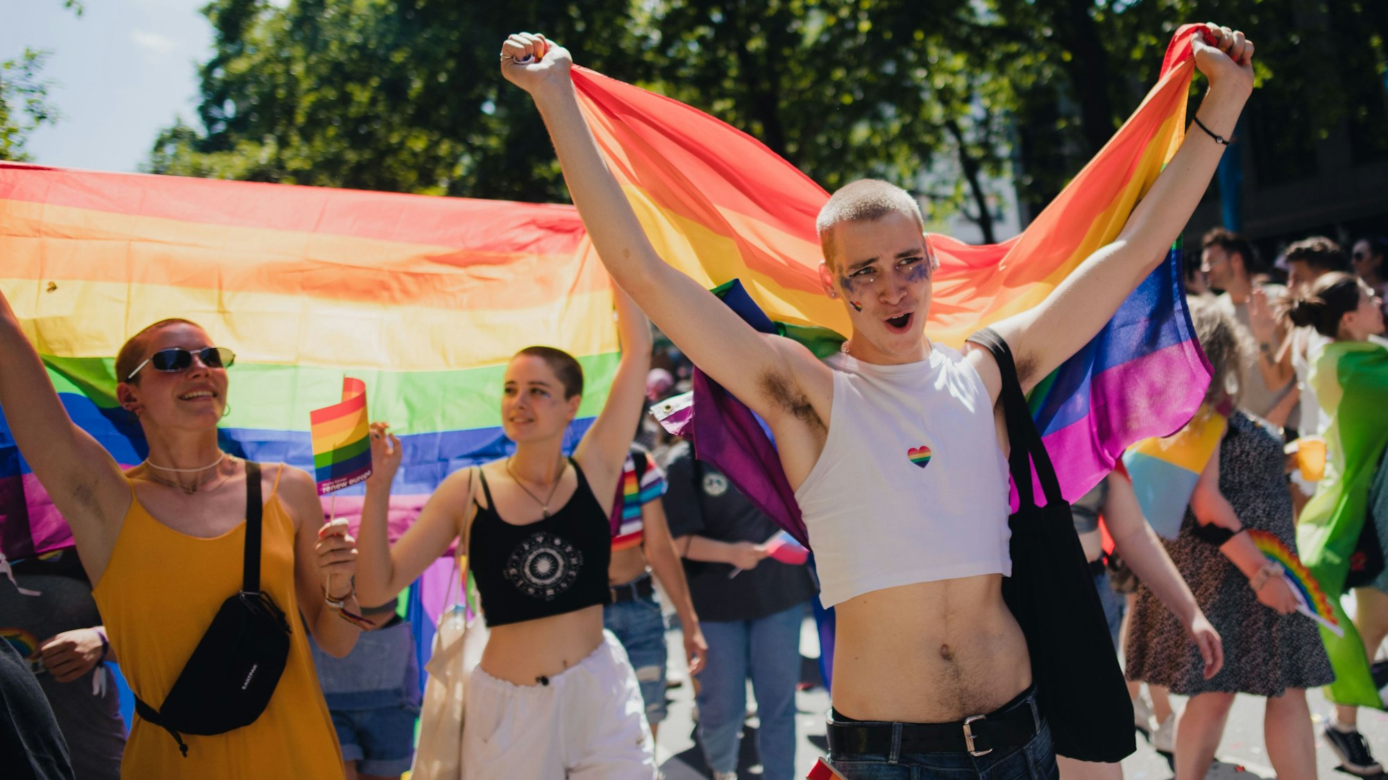 Teilnehmer einer Parade zum Christopher Street Day (CSD) ziehen mit Regenbogenfahnen durch die Stadt